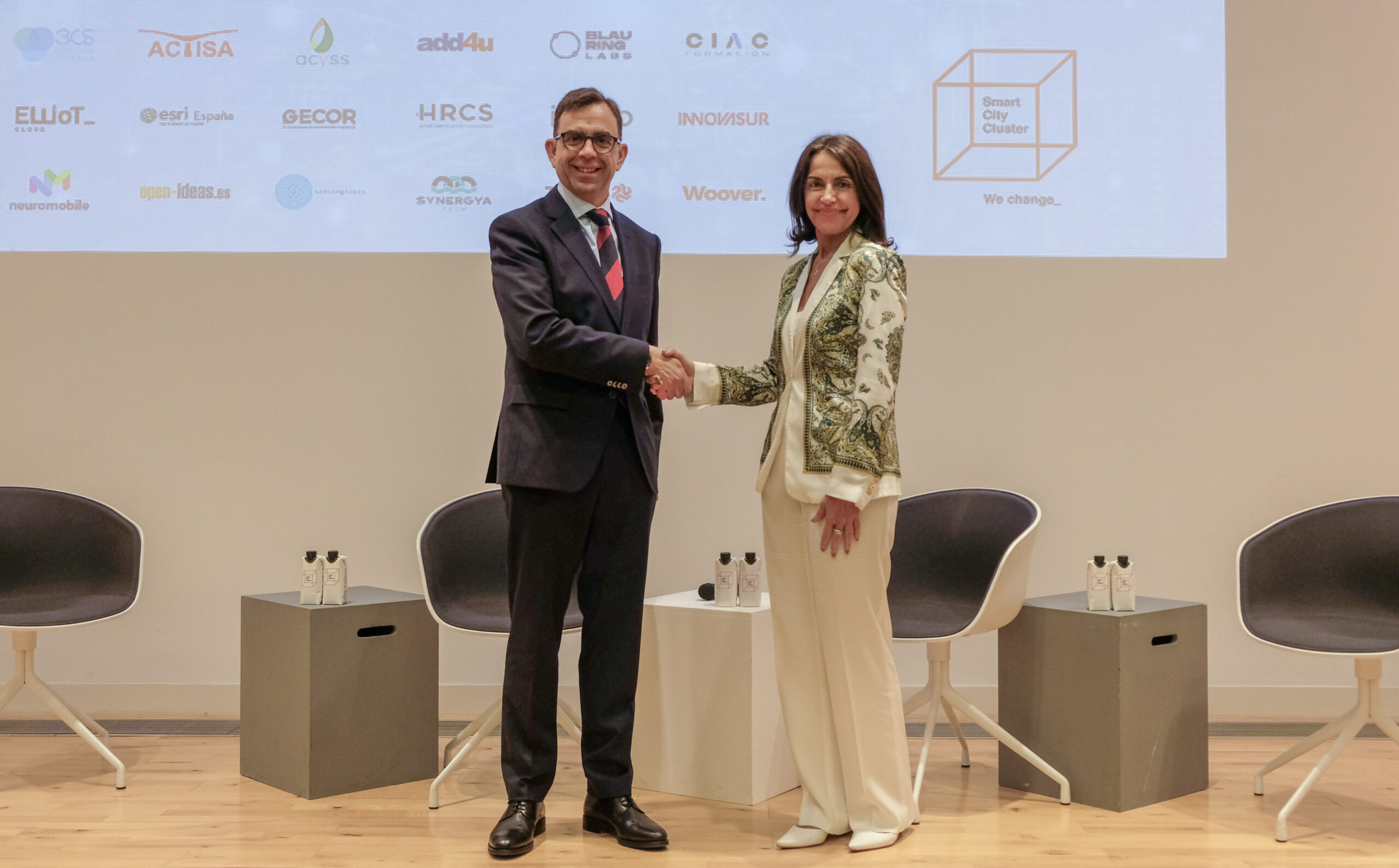 Miguel Ángel Romero, presidente de Smart City Cluster y Cristina González, directora general de Fundación Integralia, estrechan la mano en la firma del convenio